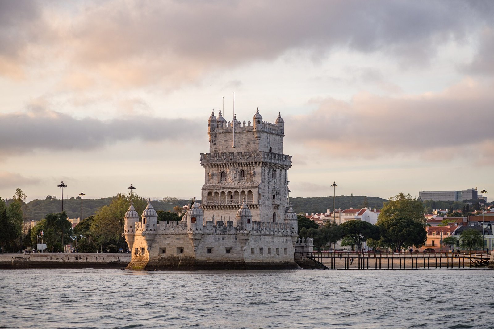The Tower of Belem surrounded by the sea and buildings under a cloudy sky in Portugal