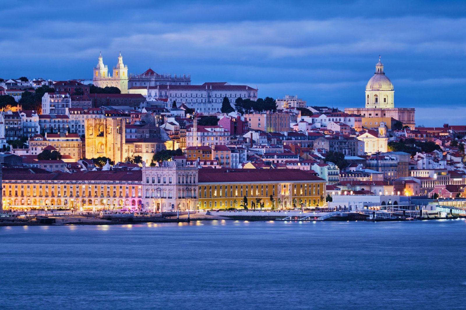 View of Lisbon over Tagus river Alfama district with National Pantheon and Monastery of St. Vincent with passing ferry boat from Almada with ferry in evening twilight. Lisbon, Portugal
